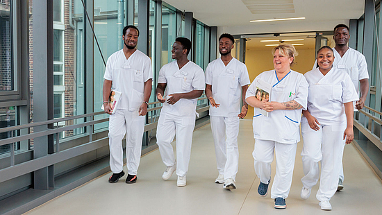 Eine Gruppe von Pflegekräften geht im Krankenhaus gemeinsam über einen Flur.