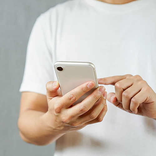 Bild zeigt einen Mann, der etwas auf einem Smartphone eingibt