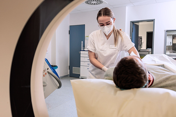 Ein Patient liegt in einem CT-Gerät und wird von einer MFA auf die Untersuchung vorbereitet